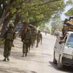 Soldiers, who are serving with the Kenyan Contingent of the African Union Mission in Somalia, patrol along a street as a commuter taxi passes by in Kismayo